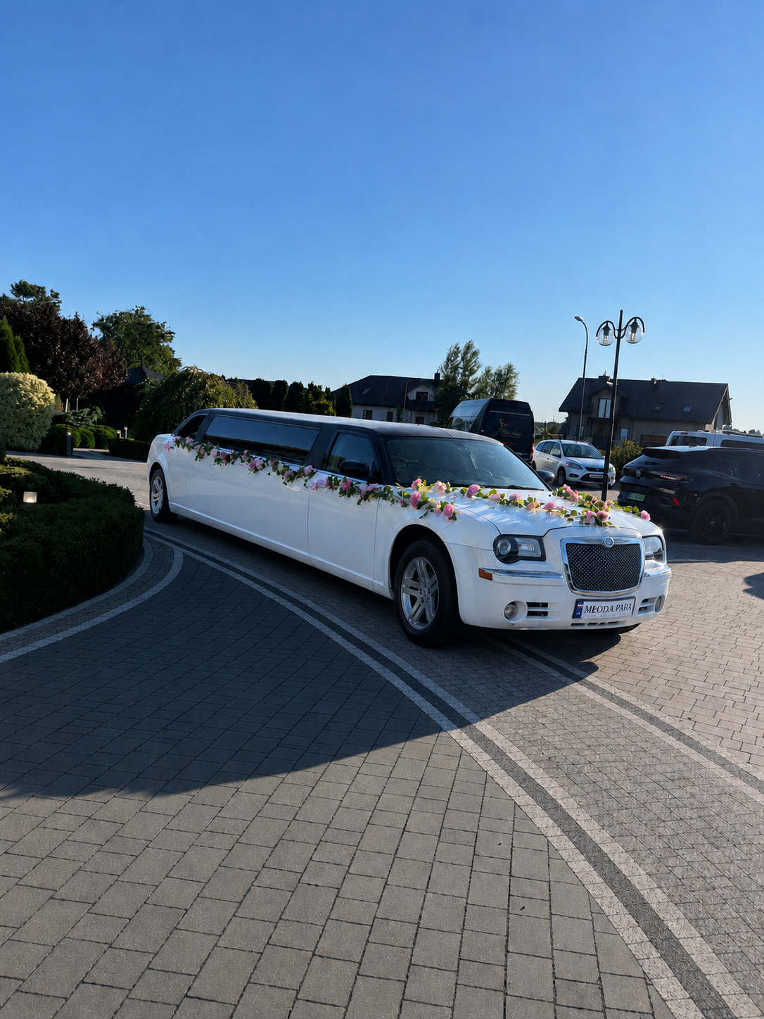 Przód limuzyny Chrysler z girlandą róż i tablicą MŁODA PARA