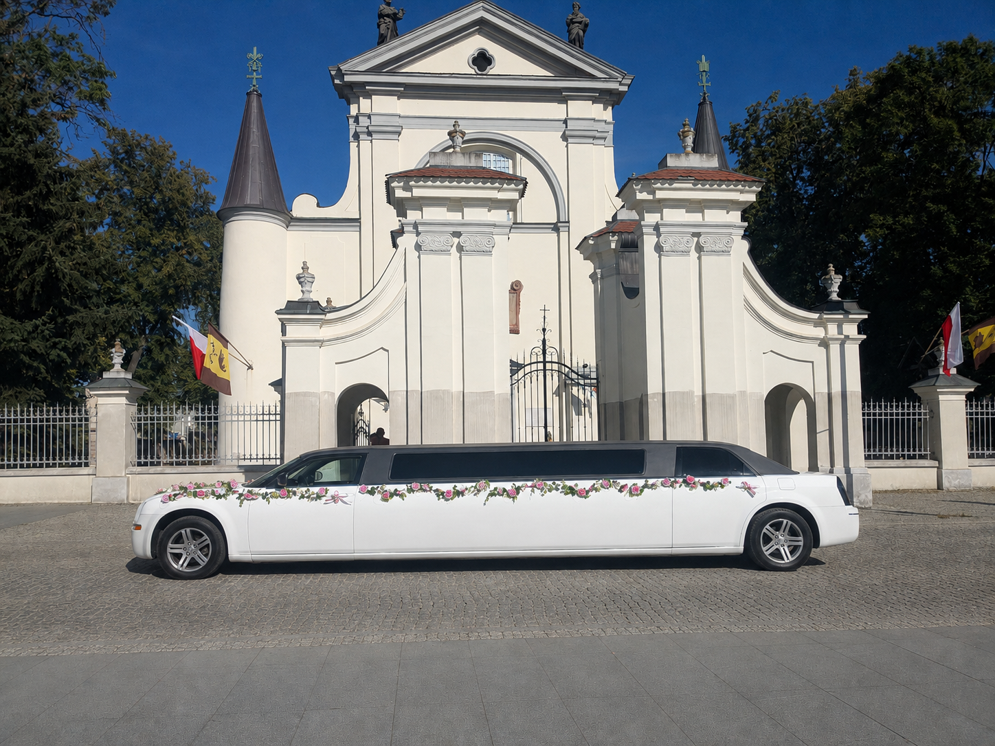 Bok limuzyny Chrysler z kwiatową dekoracją przed barokowym kościołem
