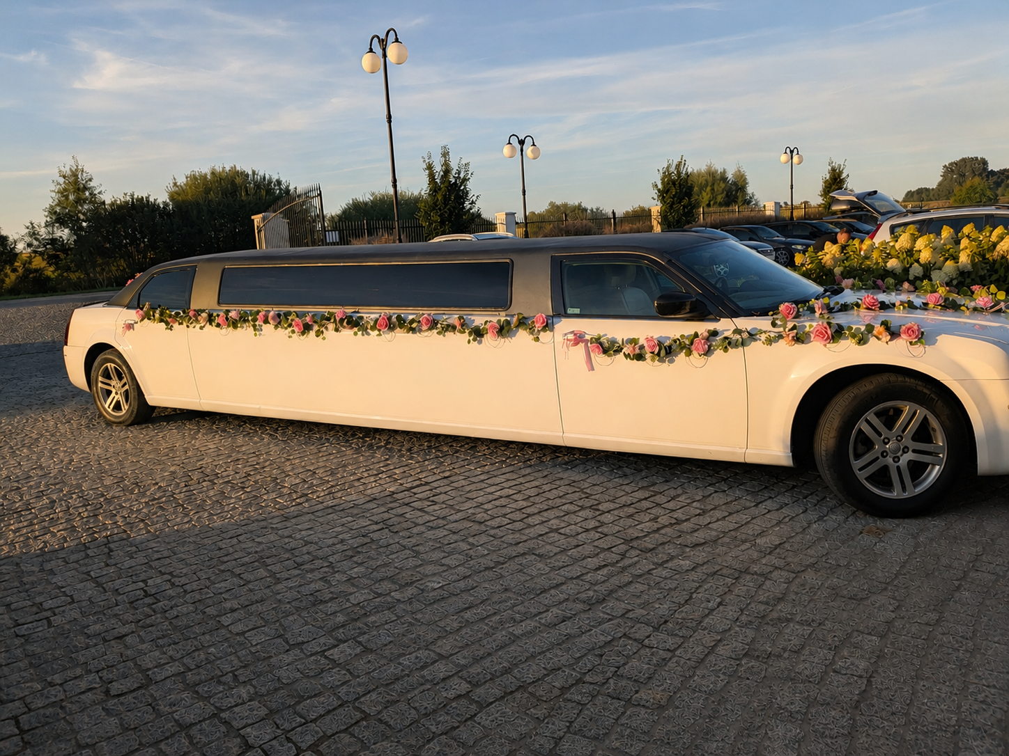 Bok udekorowanej limuzyny Chrysler na brukowanym parkingu o zachodzie słońca